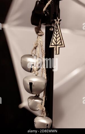 Close-up view of Festive Silver Jingle Bells and Little Wooden Tree & Star suspended from a Lighting Prop Stock Photo
