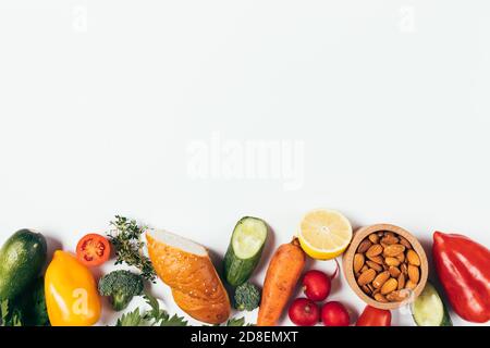 Flat lay composition of healthy food, fresh vegetables, herbs and bowl with almonds on white background with copy space Stock Photo