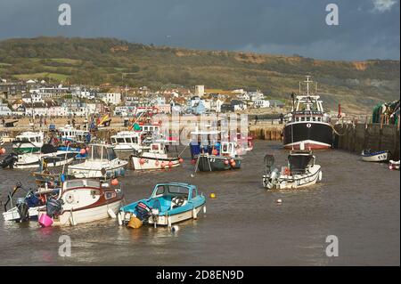 Lyme Regis, Dorset and fishing boats shelter in the harbour under stormy autumnal skies. Stock Photo