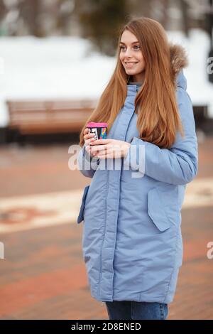 young woman walks in a winter park with coffee. winter park in the snow Stock Photo
