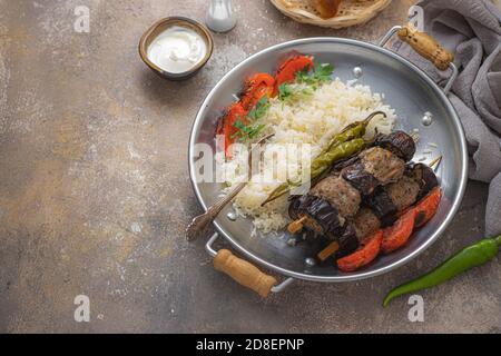 Turkish urfa kebab or eggplant kebabs on skewers with rice, copy space Stock Photo