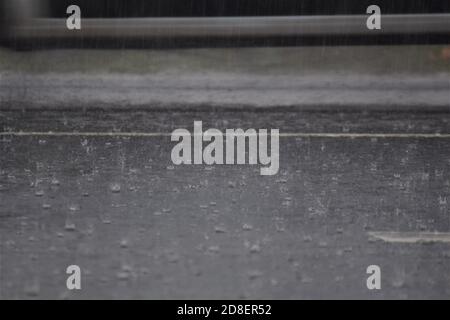 Rain on dark grey a asphalt road and some grass by the roadside Stock Photo