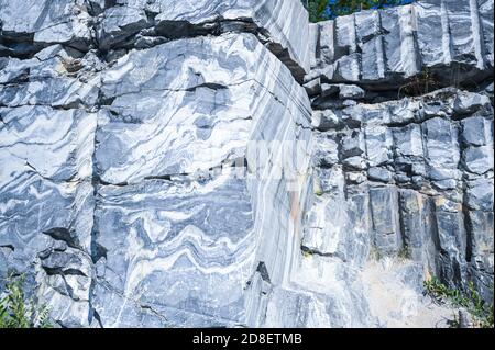 Rock cut raw surface of white and grey marble in the natural environment. Blue marble career texture. Real stone, industrial material for buildings and interior. Abstract background pattern Stock Photo
