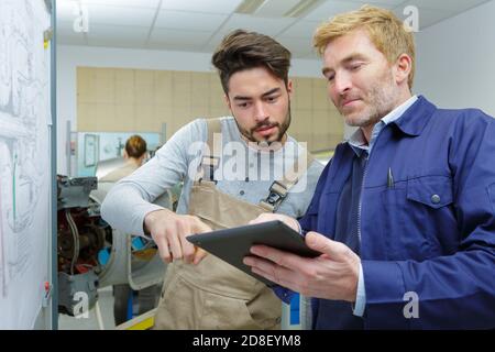 two workers with a tablet in a warehouse office Stock Photo
