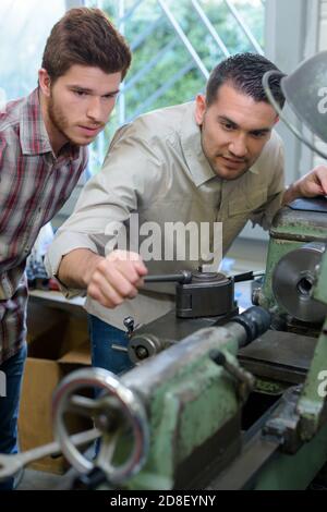 engineer teaching apprentices to use metal processing machines Stock Photo