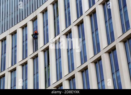 Window washer. Low Angle View of Worker Cleaning Modern Office Building. Manchester, UK. Stock Photo
