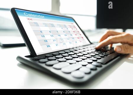 Man Looking At Calendar On Digital Tablet Stock Photo