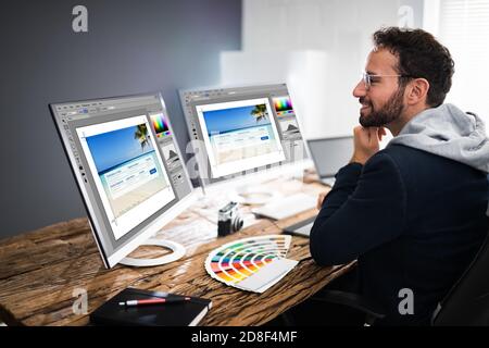 Designer Editing Photos On Multiple Computer Screens Stock Photo