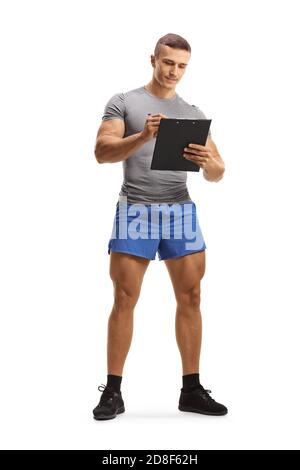 Full length portrait of a muscular young man in sportswear writing on a clipboard isolated on white background Stock Photo