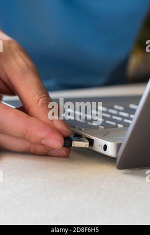 Man working on his laptop, inserting a USB nano receiver for mouse connectivity Stock Photo