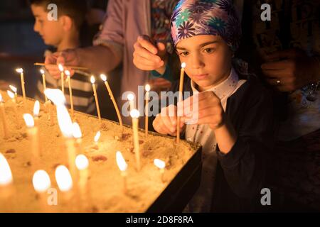 A girl lights a candle in prayer at Jvari church, one of Georgia's most holy sites in Mtskheta, Georgia, Caucasus, Europe. Stock Photo