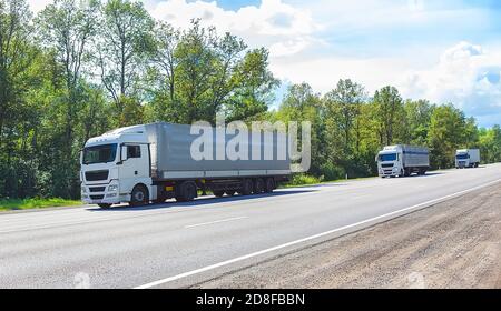 escort of trucks on country road Stock Photo