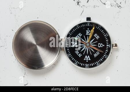An old compass with an iron lid with scratches on the textured surface of the table. Selective focus. Stock Photo