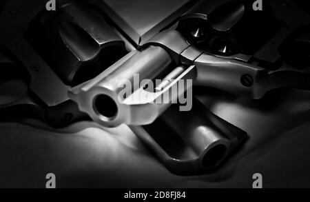 Two handguns, a stainless steel 357 and a black 38 special revolver on a black background Stock Photo