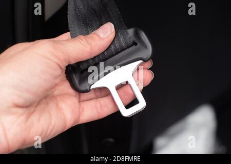 Close up of a woman's hand fastening seat belt while sitting inside a car for safety before riding on the road Stock Photo