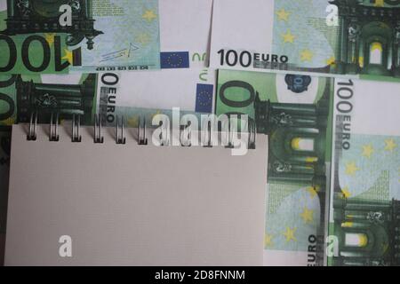 blank sheet of notebook put on 100 euros bills. Business accounting concept Stock Photo
