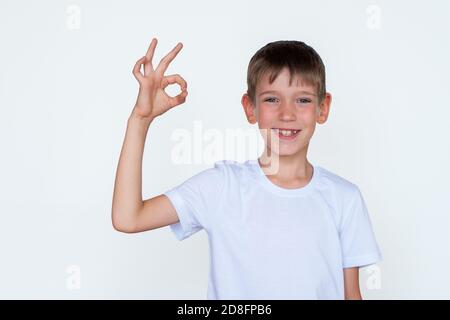 Portrait of cute Caucasian boy showing ok gesture, success, agreement on white background. Successful study concept Stock Photo