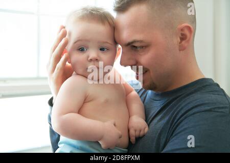 the father hugging her baby with a sad face and eyes Stock Photo