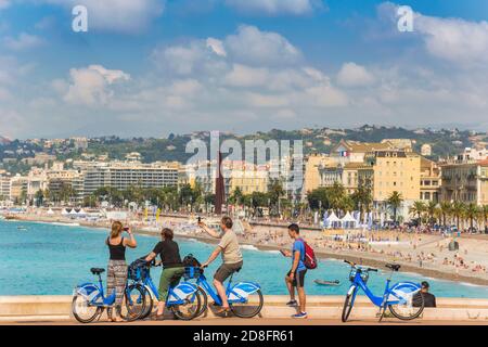 Nice, Cote d'Azur, French Riviera, France.  Cyclists taking photographs on their smart phones of the beach in front of the Nice promenade. Stock Photo