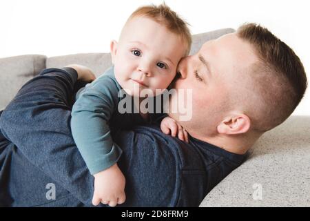 A father and baby boy playing on sofa Stock Photo