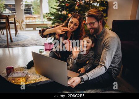 Family connecting with their loved ones online using a laptop and making a video call from home during Christmas. Christmas celebration with family ov Stock Photo
