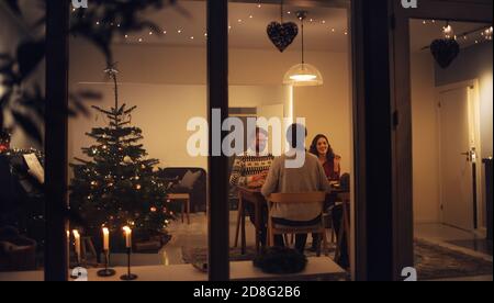 Family having a Christmas eve dinner together inside their home. European family enjoying dinner at Christmas eve in beautifully decorated home.; Stock Photo