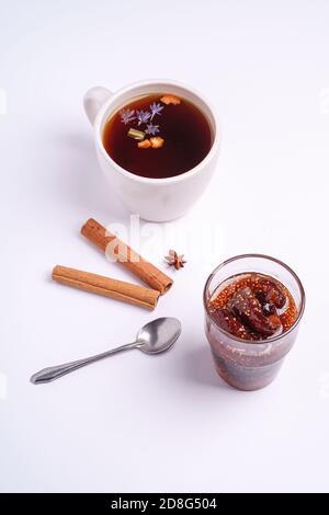 Hot black aromatic tea near to fig jam, Christmas breakfast mood with anise and cinnamon on white background, angle view Stock Photo