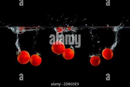 fresh tomatoes splash in water on black background Stock Photo