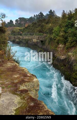 The mighty Waikato River rushing through a narrow gorge at Huka Falls, New Zealand. A bridge crosses the water Stock Photo