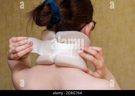 Close up of a girl fastens with a surgical neck collar, suffering from neck pain. View from the back Stock Photo