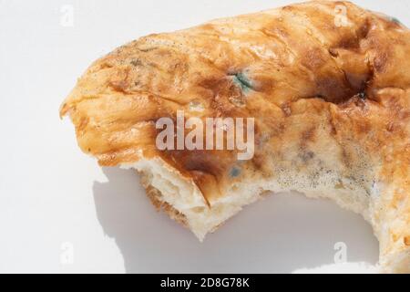 Closeup of a piece of spoiled bread with mold on a white background, copy space. The concept of spoiled food