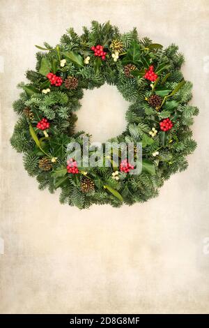 Traditional Christmas spruce fir wreath with winter berry holly, pine cones, & mistletoe on old parchment paper. Natural greenery composition for the Stock Photo