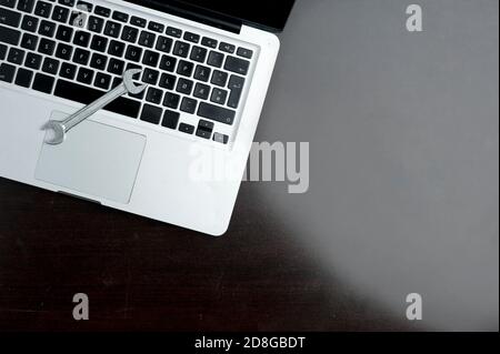 Key on laptop, close-up, on wooden table. Technical support concept Stock Photo