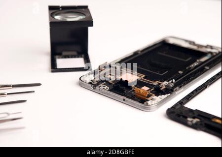 set of objects mobile repair on white background, mobile workshop concept, various tools, broken phone, magnifying glass, glue, screwdrivers, top view Stock Photo