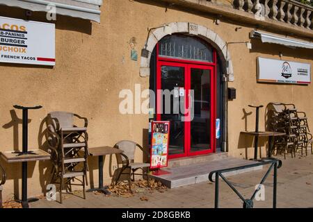 Limoux Aude France 10/29/20 Locked city cafe due to pandemic. Chairs and tables stacked beside sealed doors. Leaves on a unswept pedestrian walk way. Stock Photo