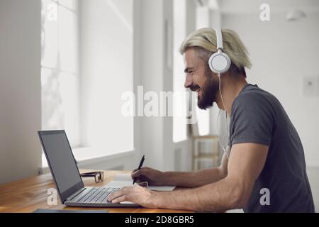 Education learning study online video call chat. Male student smiling is studying an online lesson with a teacher using a laptop webcam at home. Stock Photo