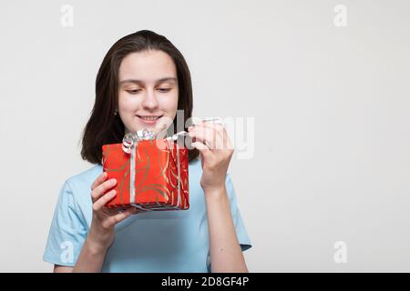 Birthday present, christmas present or new year present concept. Cute young girl holds a red gift box, opens a gift box Stock Photo