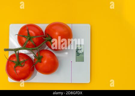 The concept of diet, proper nutrition, healthy eating. Fresh tomatoes on a branch on scale. Top view, copy space Stock Photo