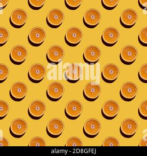 Colorful fruit seamless pattern of halves of oranges on a yellow background. Top view Stock Photo