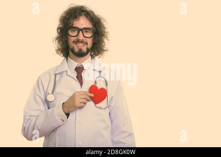 Studio shot of happy man doctor smiling holding red heart against chest Stock Photo