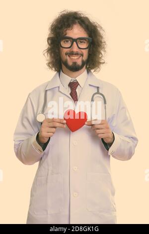 Studio shot of happy man doctor smiling holding red heart with both hands Stock Photo