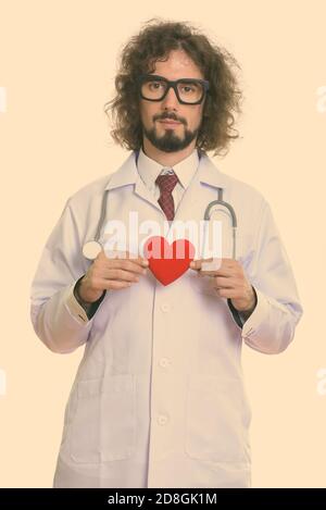 Studio shot of handsome man doctor holding red heart with both hands Stock Photo