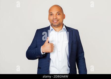Portrait of a successful young African American businessman guy making a happy hand gesture. Confirming facial expression showing success while looking at the camera. Standing on a gray background Stock Photo
