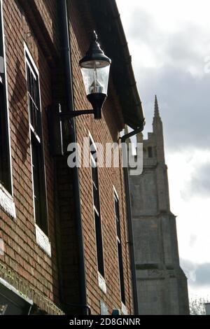 Autumn sun on a wall-mounted street lamp in Little Church Street, Wisbech, Cambridgeshire, with the parish church tower of St Peter and St Paul beyond Stock Photo