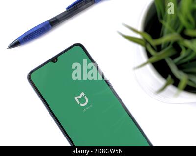 Lod, Israel - July 8, 2020: Modern minimalist office workspace with black mobile smartphone with Mi Home app launch screen with logo on white backgrou Stock Photo