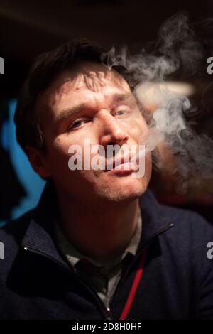 Man in a bar blows cigarette smoke Stock Photo