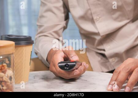 young man sitting on sofa using tv remote  Stock Photo