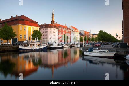Church of Our Savior spire seen behind row houses with boats docked in Copenhagen. Stock Photo