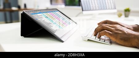 African American Working With Spreadsheet Data On Tablet Stock Photo