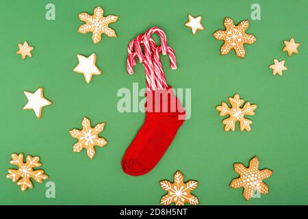 top view of red christmas stocking with candy canes near backed stars and snowflakes on green background Stock Photo